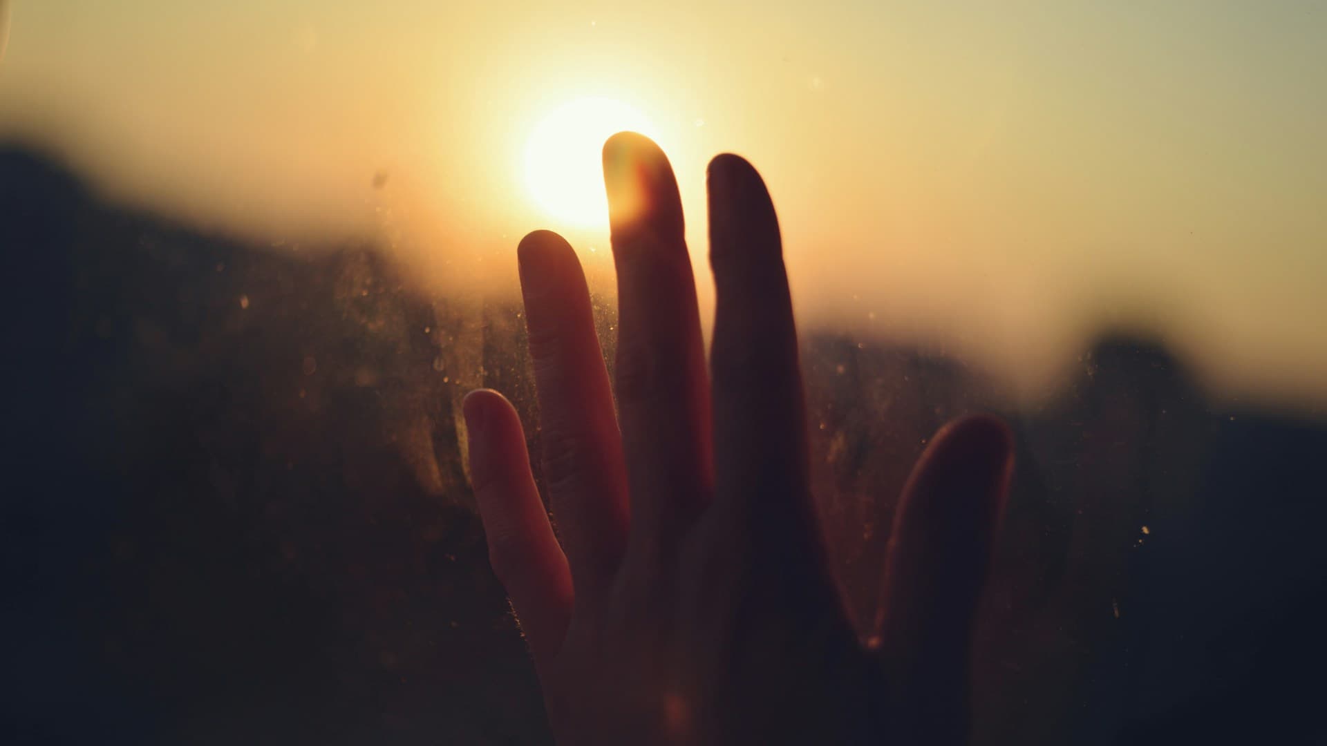 Hand reaching for hope in the sunrise - representing recovery and new beginnings